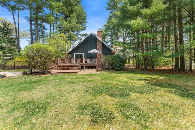 back of house featuring a lawn, fence, a chimney, and a wooden deck