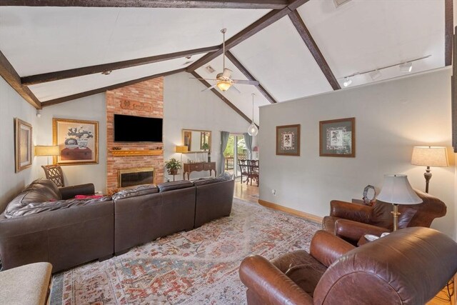 living area featuring lofted ceiling with beams, track lighting, a fireplace, ceiling fan, and baseboards