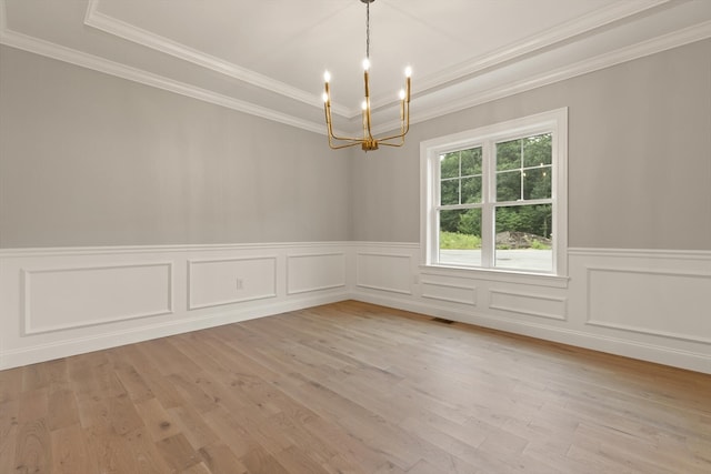 unfurnished room with light hardwood / wood-style flooring, a tray ceiling, a notable chandelier, and crown molding