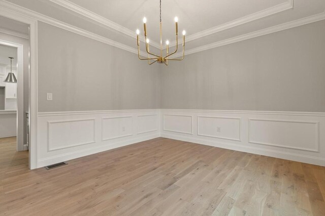 unfurnished room featuring light wood-type flooring, ornamental molding, and a chandelier