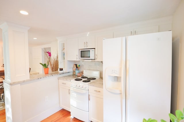 kitchen featuring white appliances, light stone countertops, backsplash, white cabinetry, and light hardwood / wood-style flooring