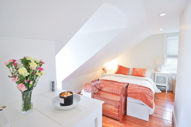 bedroom with light hardwood / wood-style floors, lofted ceiling, and baseboard heating