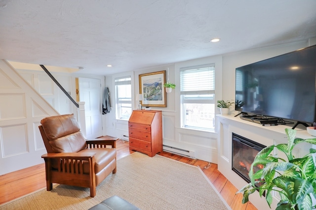 living area featuring a baseboard radiator and light hardwood / wood-style flooring