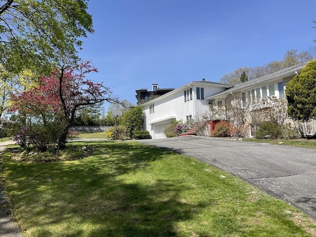 view of side of home featuring a garage, stucco siding, a yard, and driveway