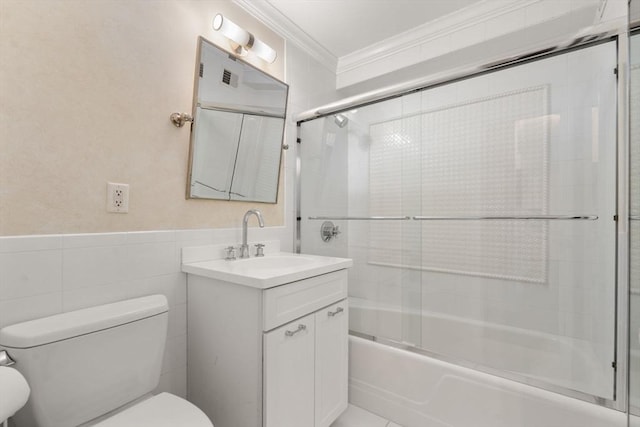 full bathroom with crown molding, tile walls, bath / shower combo with glass door, vanity, and toilet