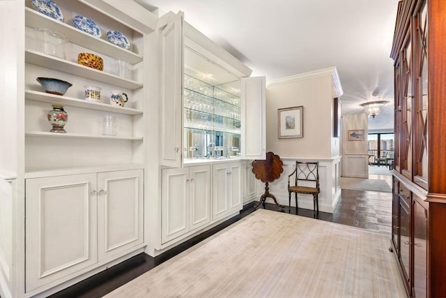 corridor featuring ornamental molding, built in features, and dark hardwood / wood-style flooring