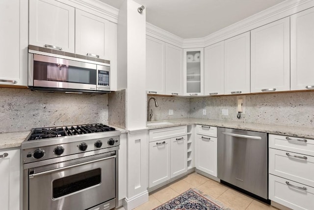 kitchen with sink, appliances with stainless steel finishes, white cabinetry, light stone countertops, and light tile patterned flooring