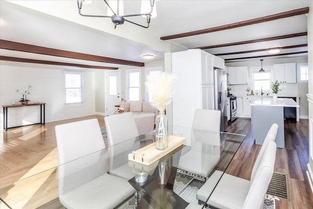 dining area featuring beam ceiling, a healthy amount of sunlight, sink, and a chandelier