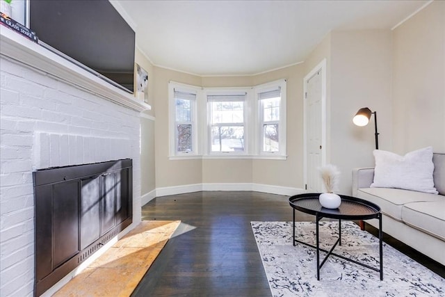 living room featuring dark hardwood / wood-style floors, a brick fireplace, and ornamental molding