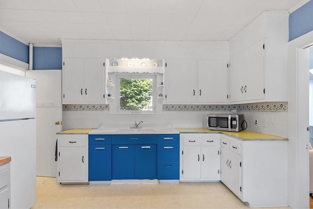 19 Franklin St, Wakefield, MA 01880 - kitchen with freestanding refrigerator, stainless steel microwave, white cabinetry, and tasteful backsplash