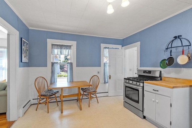 19 Franklin St, Wakefield, MA 01880 - kitchen with stainless steel gas stove, crown molding, white cabinets, wainscoting, and light flooring