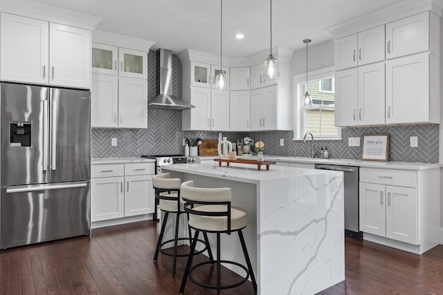 kitchen with wall chimney exhaust hood, appliances with stainless steel finishes, dark hardwood / wood-style flooring, and a kitchen island