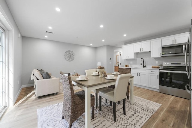 dining space with sink and light hardwood / wood-style flooring