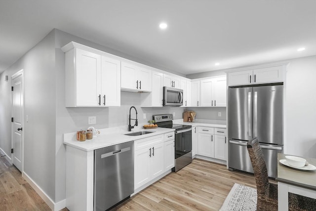 kitchen featuring white cabinetry, stainless steel appliances, sink, and light wood-type flooring