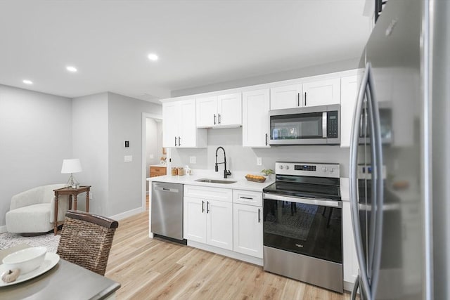 kitchen featuring white cabinetry, sink, light hardwood / wood-style flooring, and appliances with stainless steel finishes