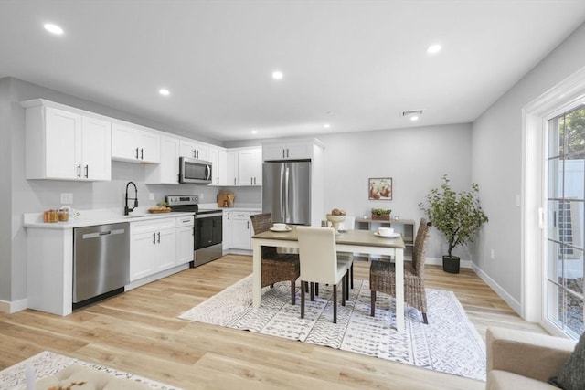 kitchen featuring stainless steel appliances, sink, white cabinets, and light wood-type flooring