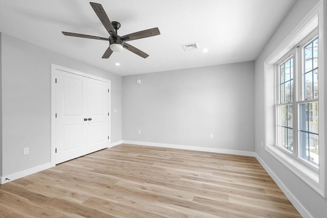 unfurnished bedroom with ceiling fan, multiple windows, a closet, and light hardwood / wood-style flooring