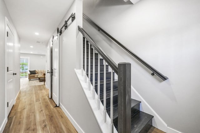 stairs with hardwood / wood-style flooring and a barn door