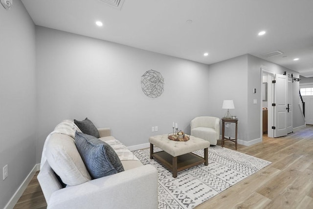 living room with a barn door and light hardwood / wood-style floors