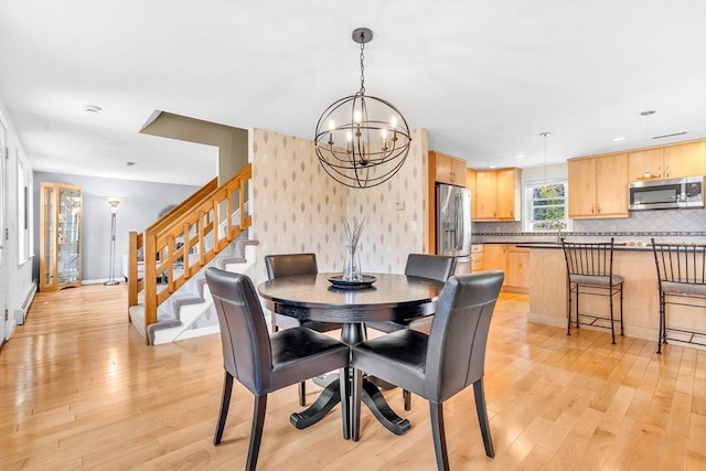 dining space with an inviting chandelier, light wood-style flooring, stairs, and wallpapered walls