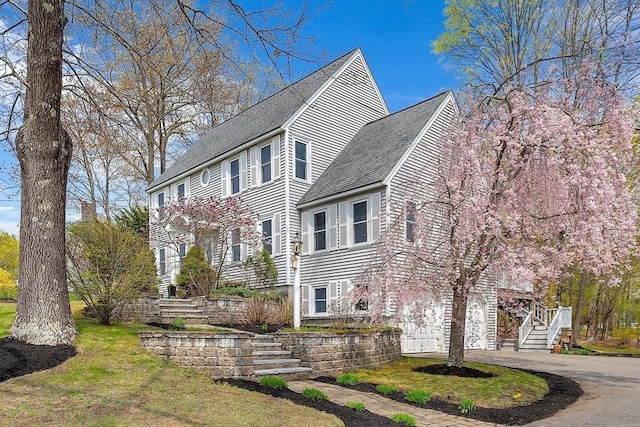 view of home's exterior featuring roof with shingles, driveway, stairway, and a garage
