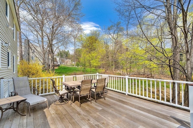 wooden deck with a lawn and outdoor dining space