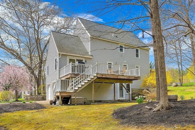 back of house featuring a lawn, roof with shingles, a wooden deck, and stairway