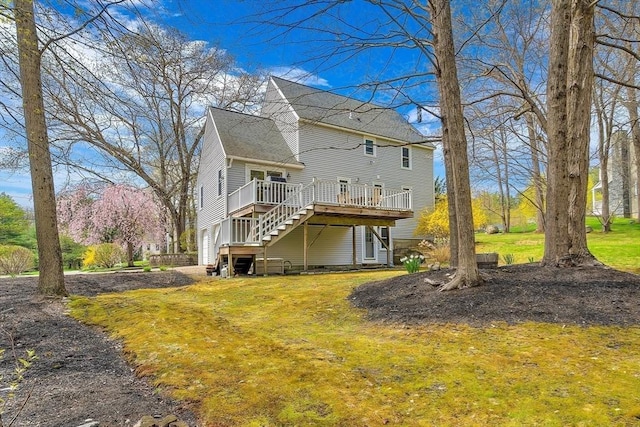 back of house featuring a lawn, a wooden deck, an attached garage, and stairway