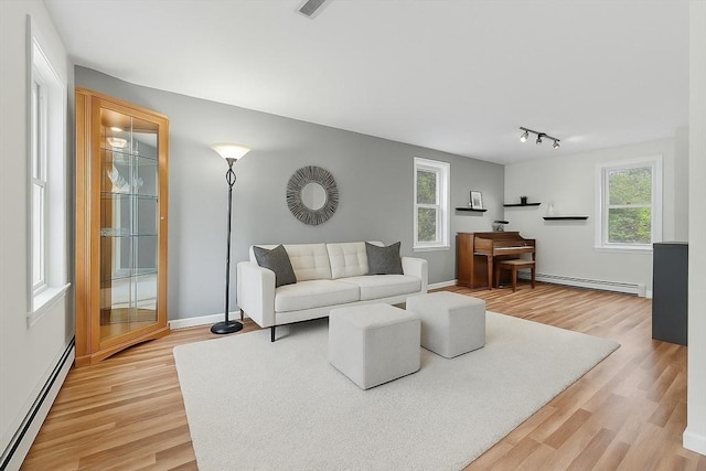 living area featuring light wood-style floors, baseboards, and a baseboard radiator