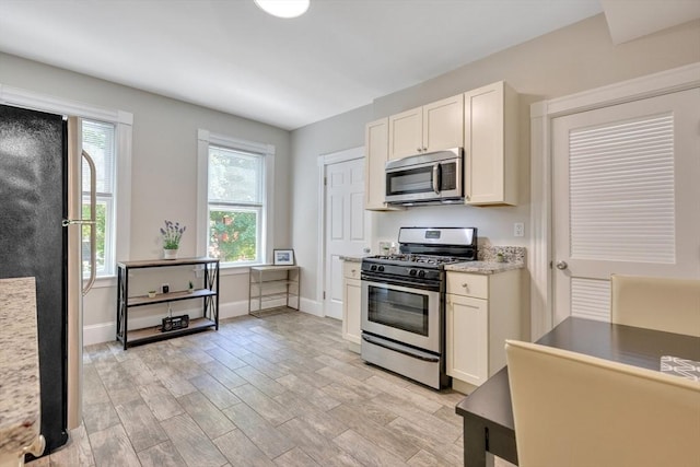 24-26 Bentley St, Boston, MA 02135 - kitchen with stainless steel appliances, light wood-type flooring, white cabinetry, and light stone counters
