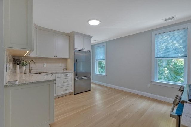 24-26 Bentley St, Boston, MA 02135 - kitchen with built in refrigerator, light wood-type flooring, backsplash, light stone countertops, and range
