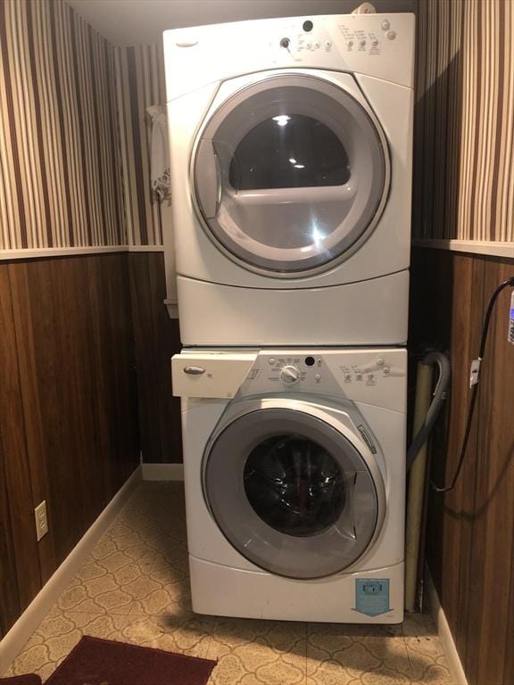 laundry area featuring stacked washer / dryer and wooden walls