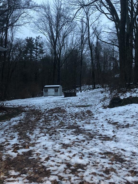 yard layered in snow with a storage unit