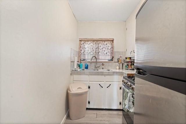 376 N Underwood St, Fall River, MA 02720 - kitchen with stainless steel appliances, white cabinetry, decorative backsplash, light wood-style floors, and light countertops