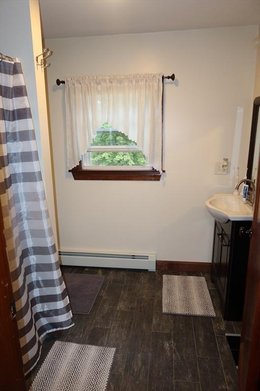 17 Lockwood Ave, Attleboro, MA 02703 - full bath featuring a baseboard heating unit, vanity, wood finished floors, curtained shower, and baseboards