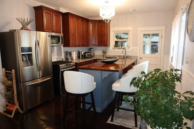 17 Lockwood Ave, Attleboro, MA 02703 - kitchen featuring appliances with stainless steel finishes, a chandelier, butcher block countertops, a sink, and a wainscoted wall