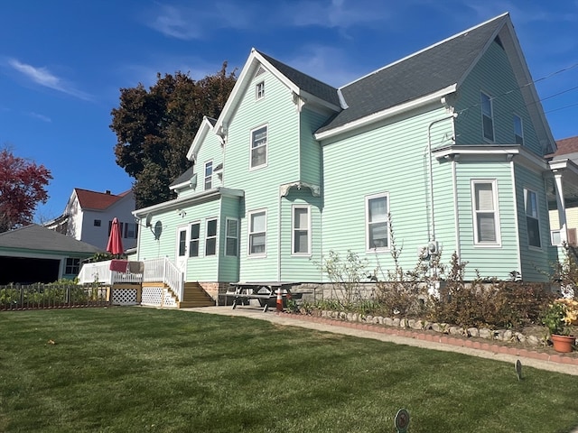 rear view of property featuring a lawn and a deck