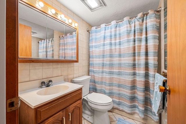 bathroom with tile walls, tile patterned flooring, toilet, vanity, and a textured ceiling