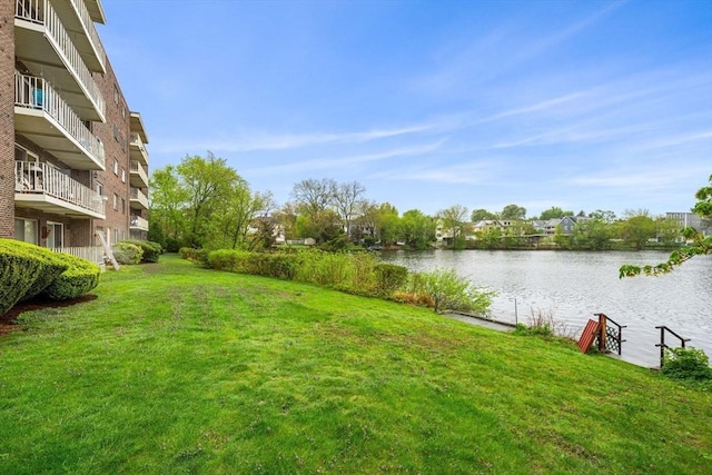 view of green lawn with a water view