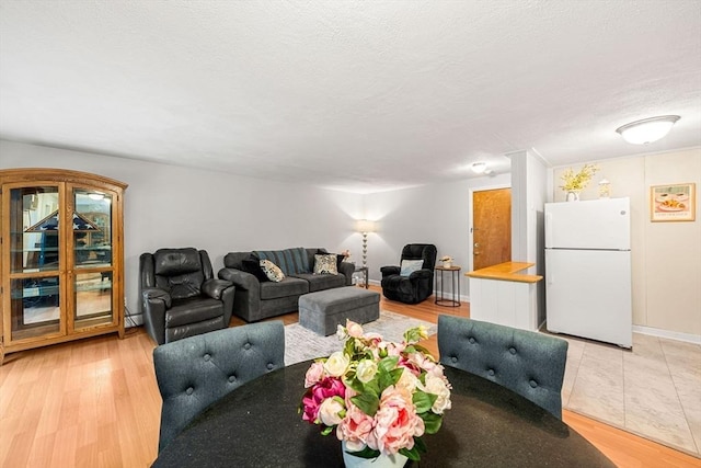 living area with light wood-style floors, a textured ceiling, and baseboards