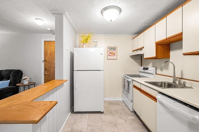 kitchen featuring white appliances, a sink, a textured ceiling, light countertops, and white cabinets