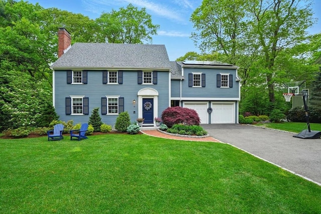 12 Olde Lyme Rd, Winchester, MA 01890 - view of front of property featuring a chimney, a garage, asphalt driveway, and a front yard