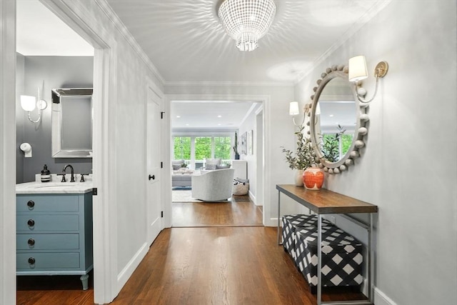 12 Olde Lyme Rd, Winchester, MA 01890 - corridor featuring a chandelier, dark wood-type flooring, a sink, baseboards, and crown molding
