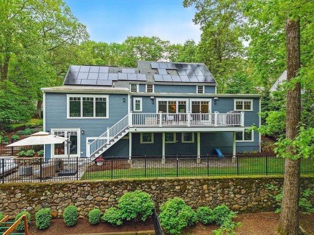12 Olde Lyme Rd, Winchester, MA 01890 - rear view of property featuring stairway, a deck, a patio, roof mounted solar panels, and a fenced backyard