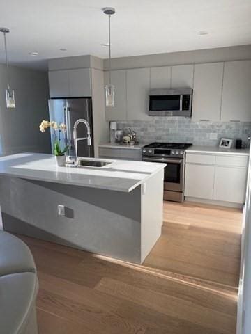 16 Boardman St Unit 204A, Boston, MA 02128 - kitchen featuring stainless steel appliances, a sink, hanging light fixtures, light countertops, and tasteful backsplash