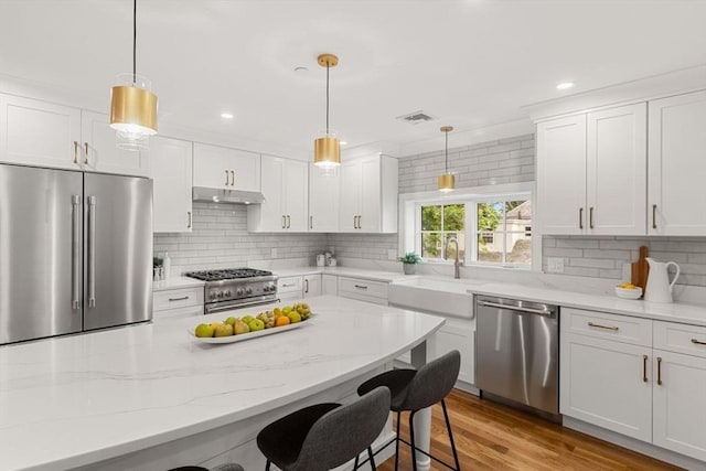 kitchen featuring high end appliances, white cabinetry, and pendant lighting