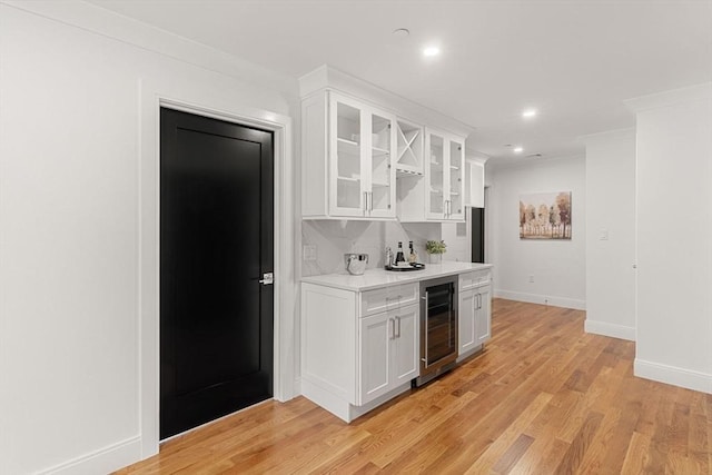 bar with light hardwood / wood-style floors, wine cooler, white cabinets, and tasteful backsplash