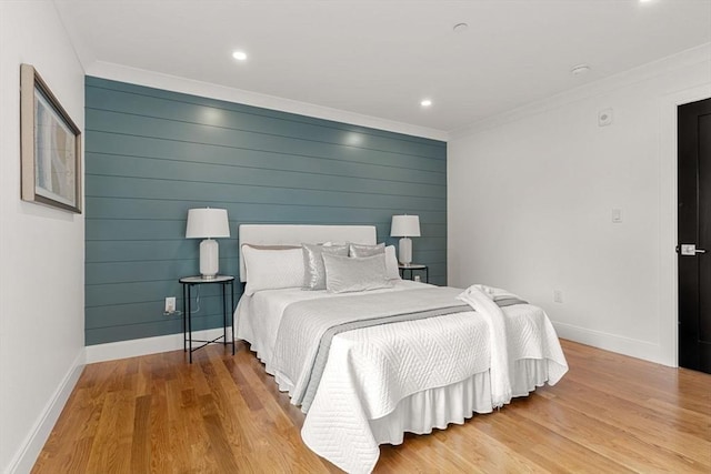 bedroom with light wood-type flooring, wooden walls, and crown molding