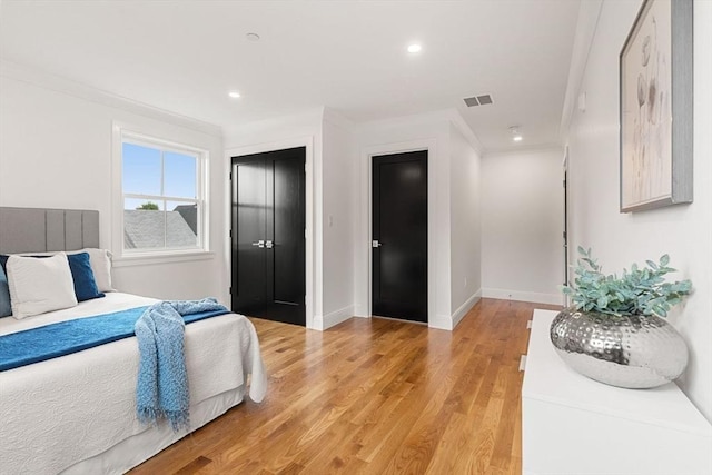 bedroom featuring ornamental molding and light hardwood / wood-style floors