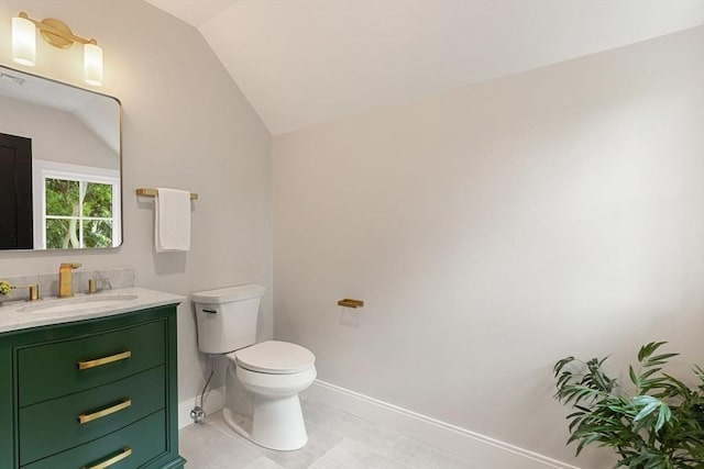 bathroom with toilet, lofted ceiling, tile patterned floors, and vanity